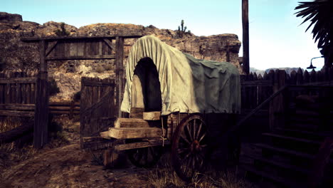 rustic wagon resting at a wooden gate in a desert landscape