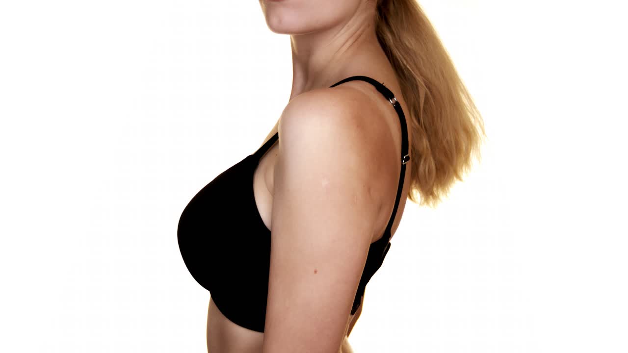 Close-up of a woman's torso with big breasts in a black bra