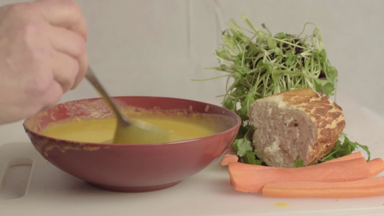 Hand stirring fresh carrot and coriander soup