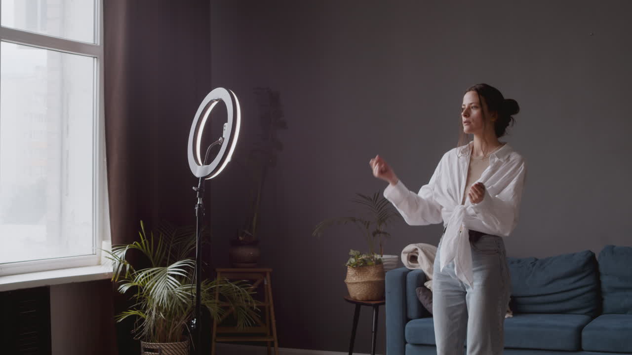 젊은 틱토커 소녀가 휴대폰 카메라 앞에서 몇 가지 댄스 스텝을 리허설합니다.