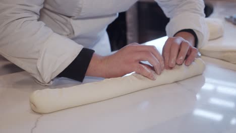 Chef-forming-bread-dough-on-cooking-table-in-the-restaurant