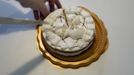 close-up of men's hands cutting a white cream cake into identical pieces on a yellow plate with a large kitchen knife. the concept of the holiday. faceless. top view. 4k.