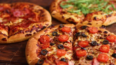 Various-kinds-of-pizzas-placed-on-wooden-table