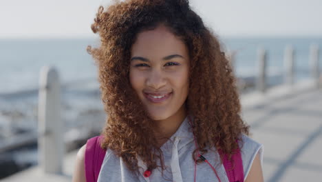 Retrato-Hermosa-Mujer-De-Raza-Mixta-Sonriendo-Disfrutando-De-Un-Exitoso-Estilo-De-Vida-De-Vacaciones-Relajante-Mujer-Joven-Que-Parece-Feliz-En-Un-Cálido-Fondo-Costero-Peinado-Rizado