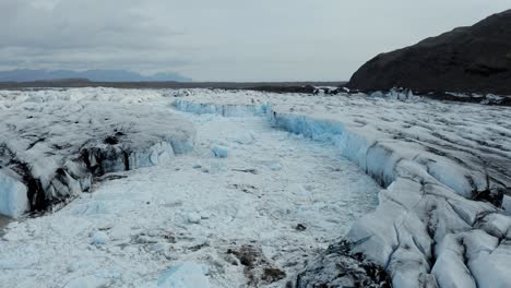 Antena-Baja-Sobre-El-Glaciar-Muestra-Un-área-Erosionada-Con-Hielo-Flotante-En-Un-Lago-Glacial