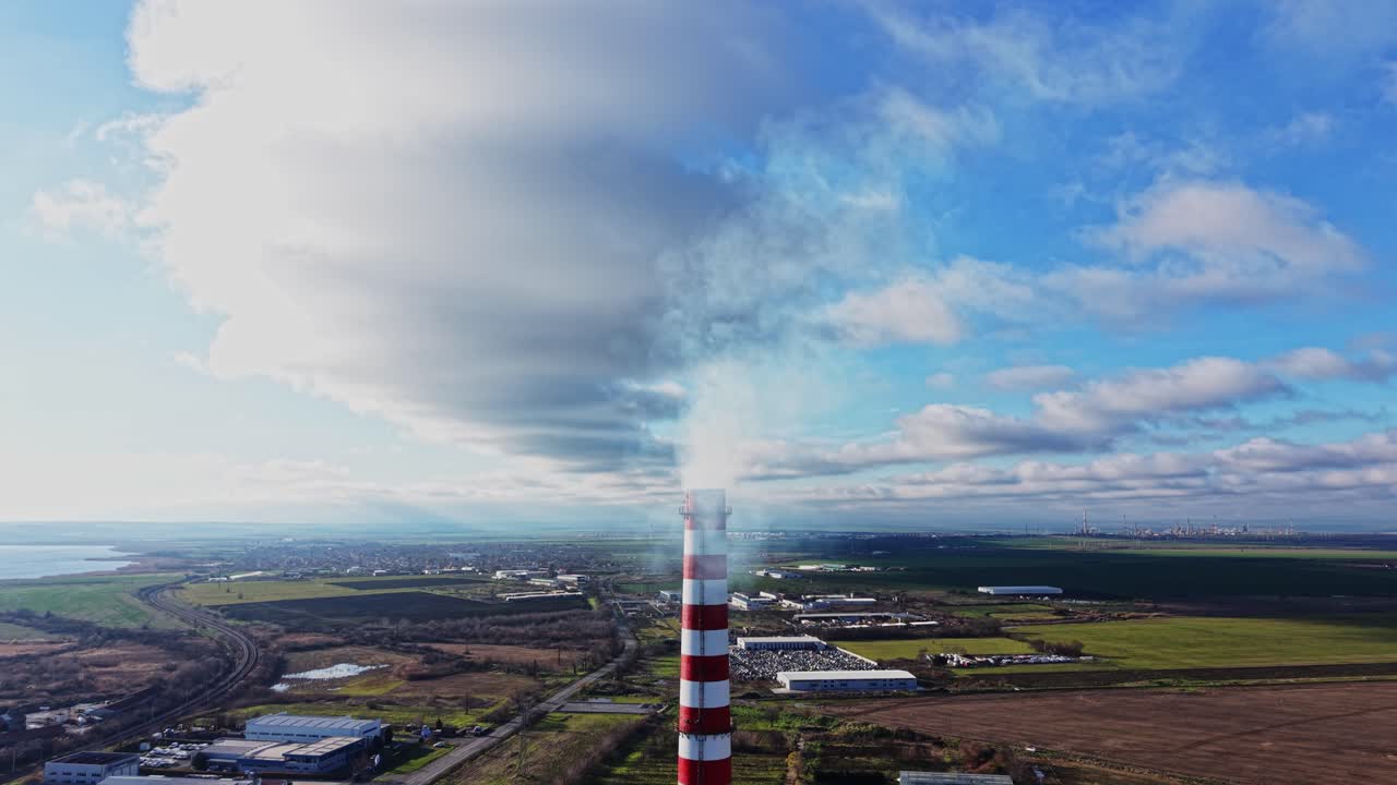 Smoke rising from a tall factory chimney in a clear sky