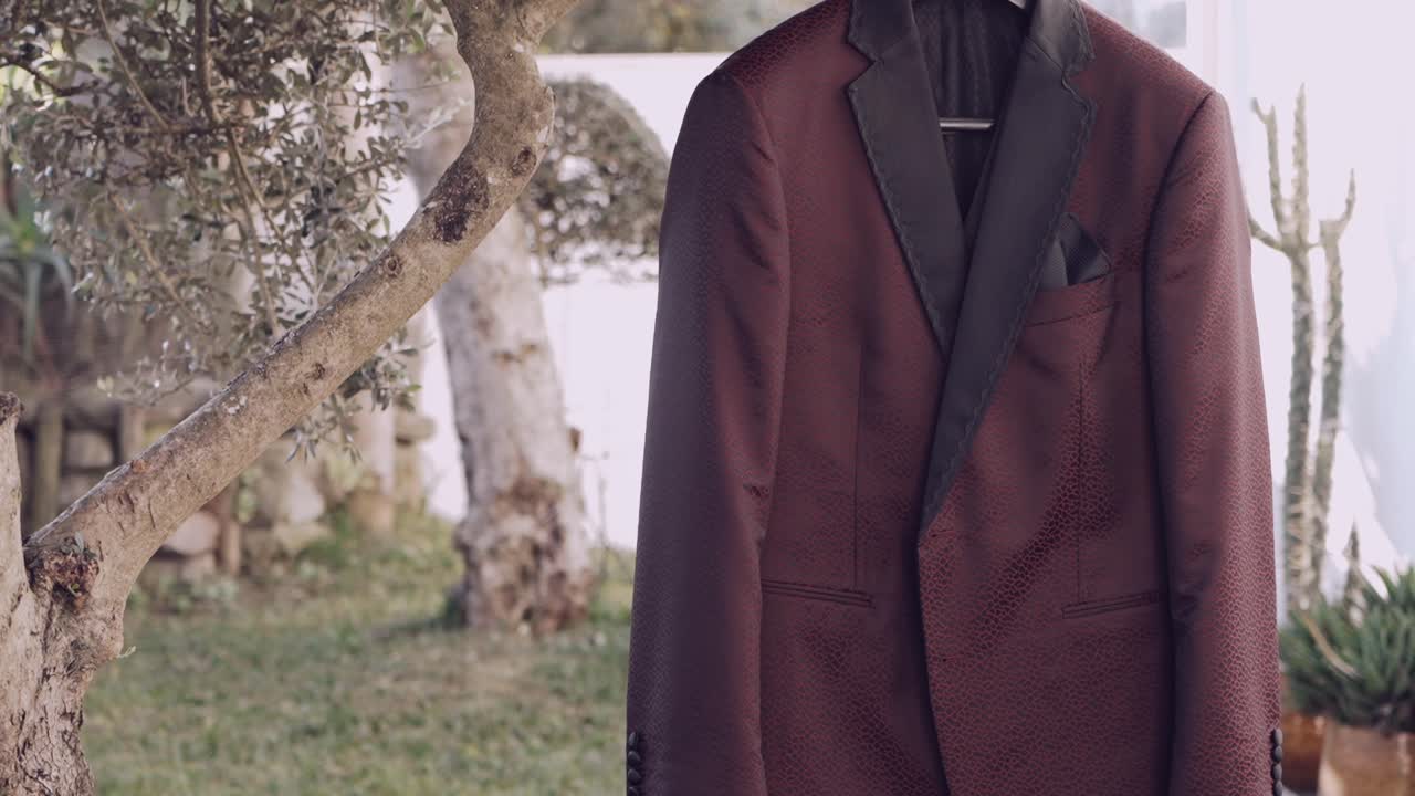 Stylish dark tuxedo jacket with black lapel hanging on a tree outdoors