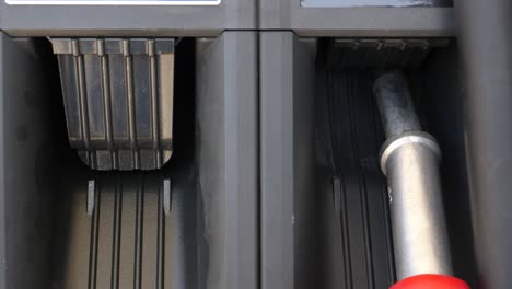 primer plano de una boquilla de combustible que se retira y se vuelve a colocar en la bomba de gasolina en una gasolinera