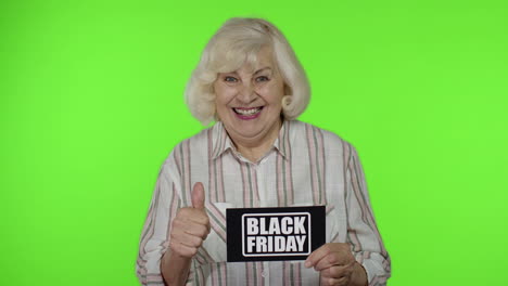 Senior-grandmother-showing-Black-Friday-inscription-note,-smiling,-looking-satisfied-with-low-prices