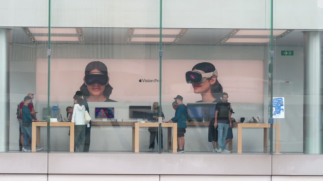 While customers browse for Apple products at the store of the American tech giant, a poster displaying the Apple Vision Pro, the company's new mixed-reality headset, can be seen in the background.