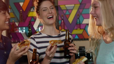 friends eating pizza while having beer