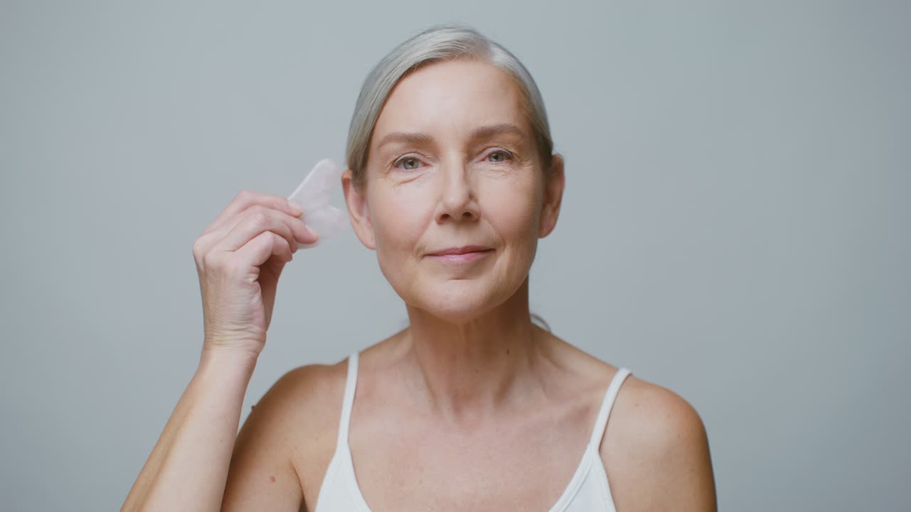 masaje facial de gua sha por una mujer madura