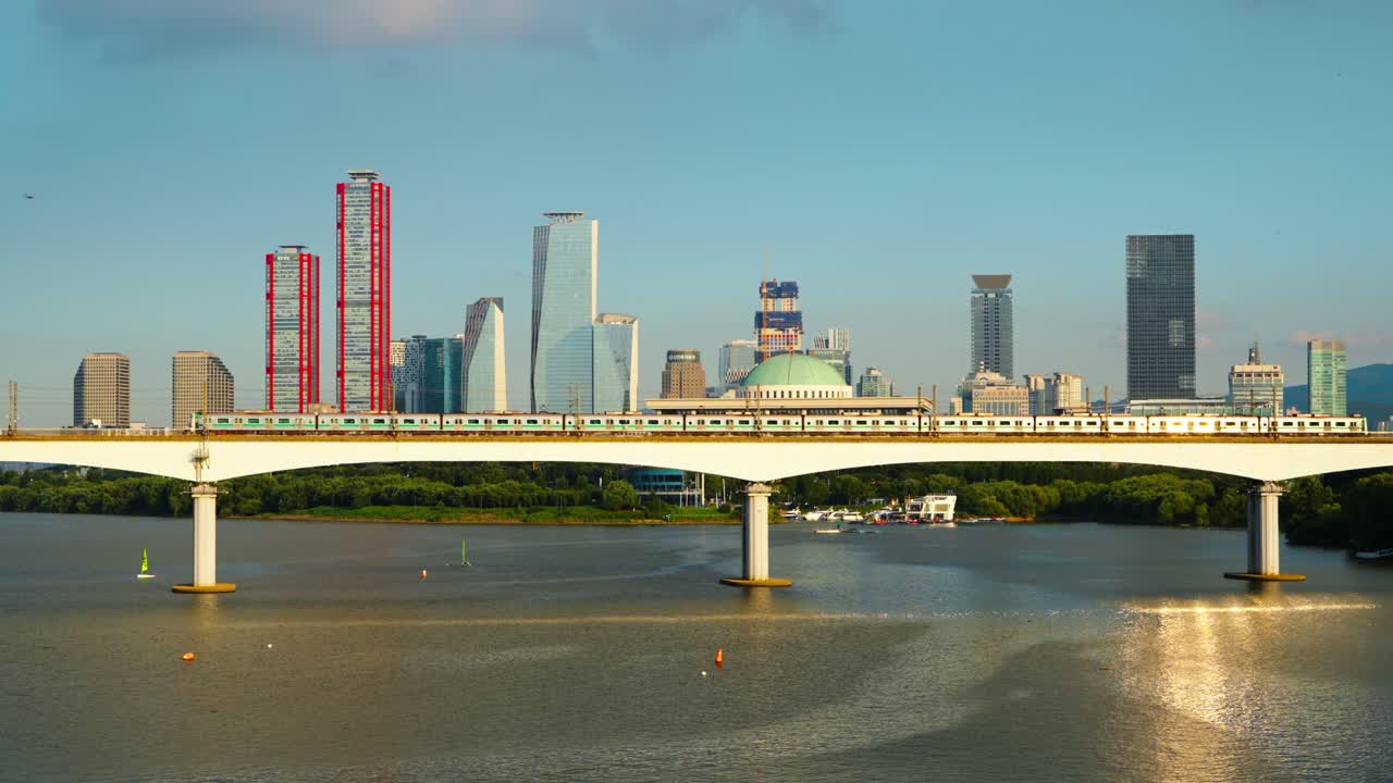 View of Seoul Line 2 subway train crossing Dangsan Railway Bridge over the Han River, with Yeouido skyscrapers and National Assembly Building in the background lit with sunset sunlight