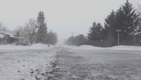 Bodennahe-Aufnahme-Von-Schnee,-Der-In-Einem-Schneesturm-In-Bozeman,-Montana,-über-Den-Straßenrand-Weht