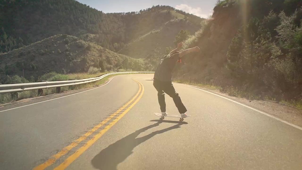Um skatista descendo em alta velocidade uma colina íngreme no interior do Colorado em um skate.