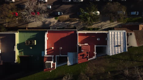 the drone flies from the road towards the park past the roof of the house, the car passes along the road