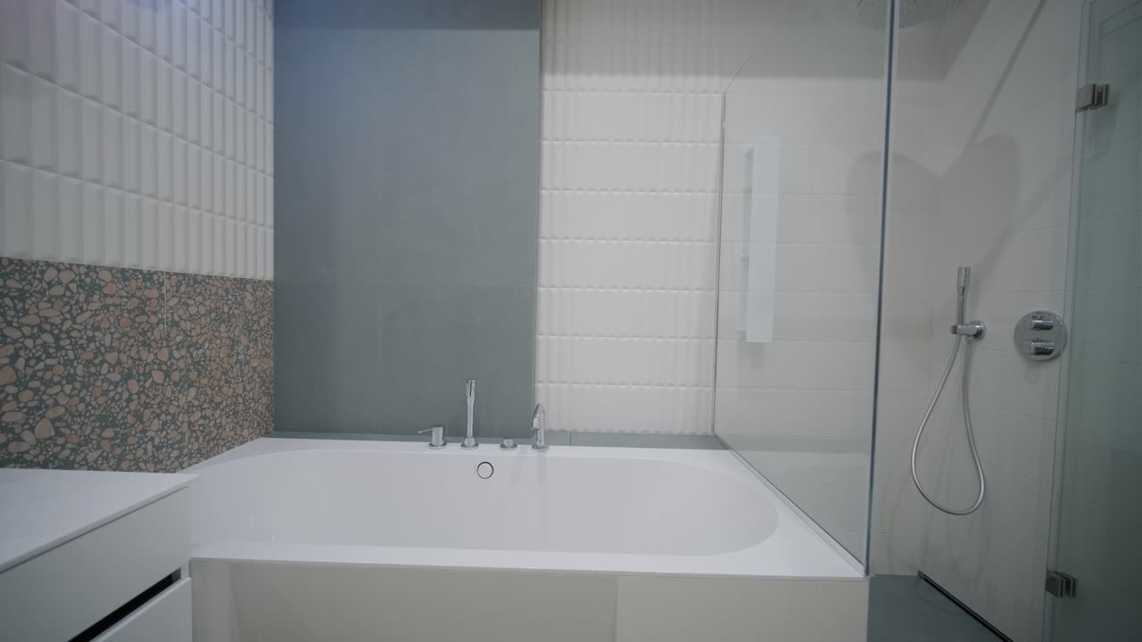 현대적인 욕실 인테리어는 테라조 바닥, 지하철 타일 목욕탕, 유리로 둘러싸인 샤워 공간, 독특한 거울과 다채로운 펜던트 조명과 함께 푸른색 욕조 허영을 특징으로합니다.