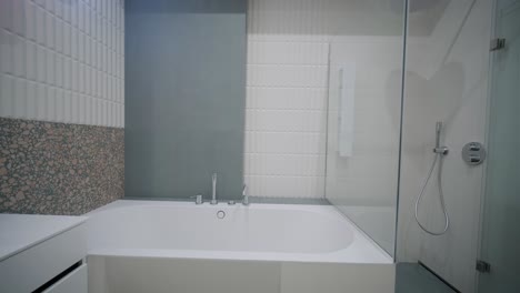 interior de baño moderno con suelo de terrazo, una bañera de azulejos de metro, una zona de ducha cerrada con vidrio y una vanidad de lavabo de azul azulado con un espejo único y luces colorado colgante