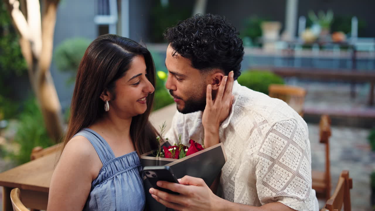 Coppia felice condivide un momento romantico guardando uno smartphone con rose