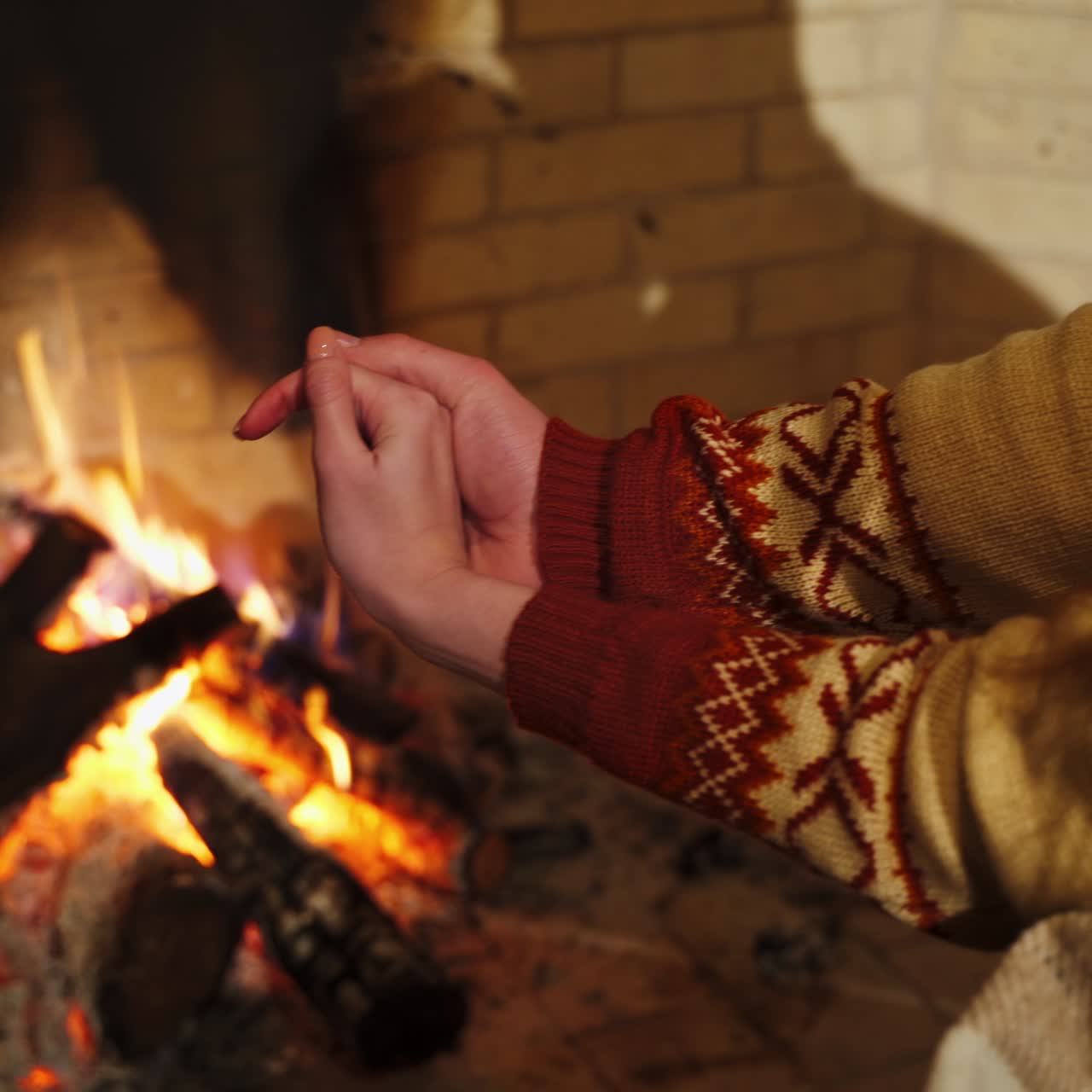 Male is warming hands near the bonfire at the twilight's inside. Fireplace in a house. Cold season concept