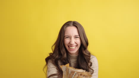 excited woman celebrating with cash against yellow background