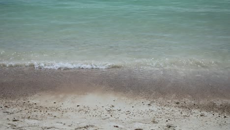 glistening turquoise ocean water gently cascading onto pristine white sand beach. creating foamy waves adding serenity to stunning seascape. inviting relaxation and soaking in nature's beauty