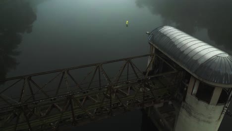 an abandoned tower-like lock structure on a river covered in morning mist