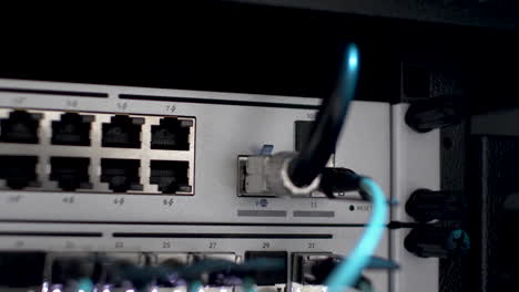 close up shot of fibre optic cable plugged in network server rack with white blinking lights