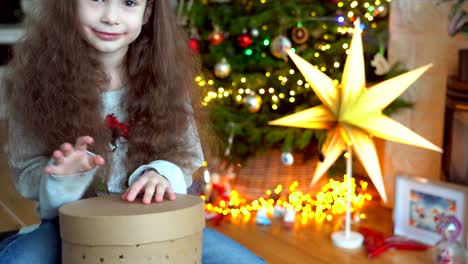 retrato de una niña feliz sentada cerca del árbol de navidad en la víspera de año nuevo en una habitación decorada. año nuevo y vacaciones con conceptos para niños. disfrutando de una celebración festiva.
