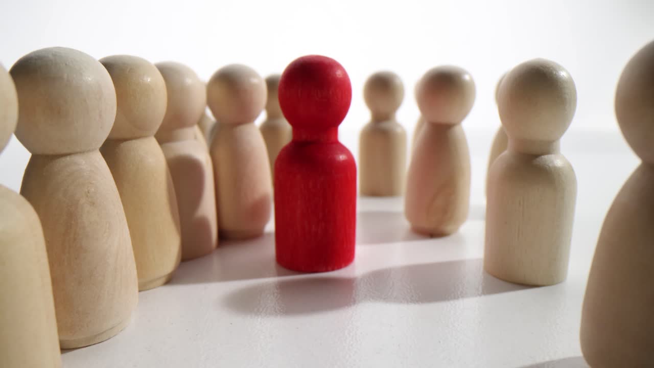 Red Pawn Standing Out Among Wooden Figures