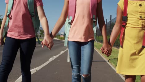 group of kids holding hands while walking on the road