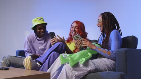 fotografía de estudio de un grupo de amigos de la generación z sentados en el sofá jugando y usando las redes sociales en los teléfonos móviles 2