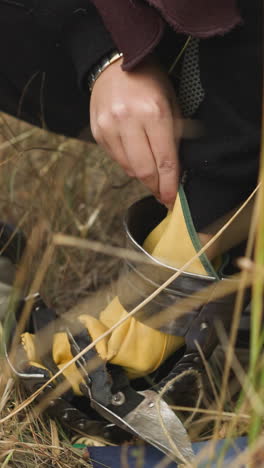 couple of young men examines knight gauntlet on ground. man puts on part of armor on arm carefully and looks at palm. medieval artifact closeup