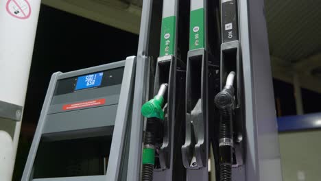 Person-picks-up-green-unleaded-fuel-handle-to-begin-refueling-car's-tank-on-a-petrol-station