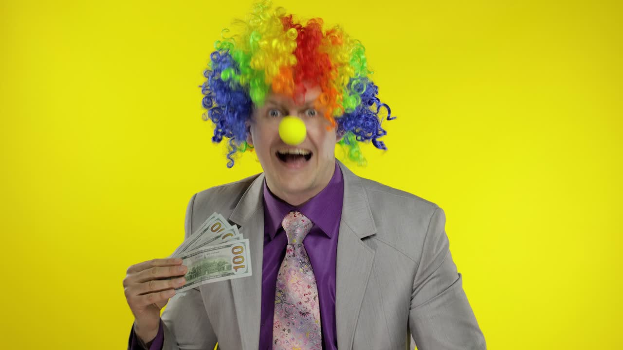 Clown businessman entrepreneur boss in wig waves with money banknotes. Halloween