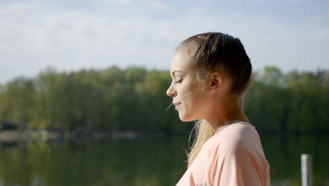 Mujer-En-La-Orilla-Del-Lago-Respirando-Profundamente-Y-Viendo-El-Lago