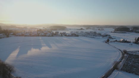 Cinematic-drone-shot-flying-towards-a-small-village-in-the-winter-as-the-sun-rises