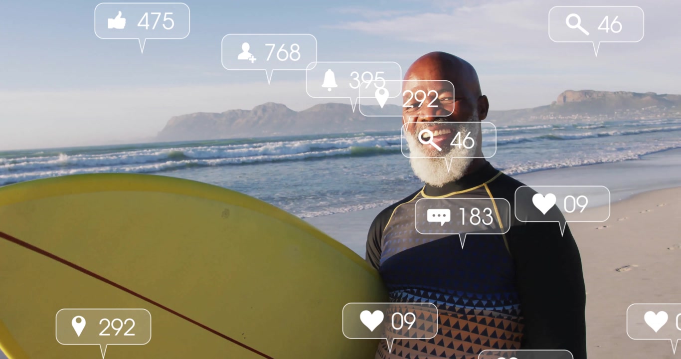 Mature male surfer laughing holding surfboard with social icons floating updating engagement counts