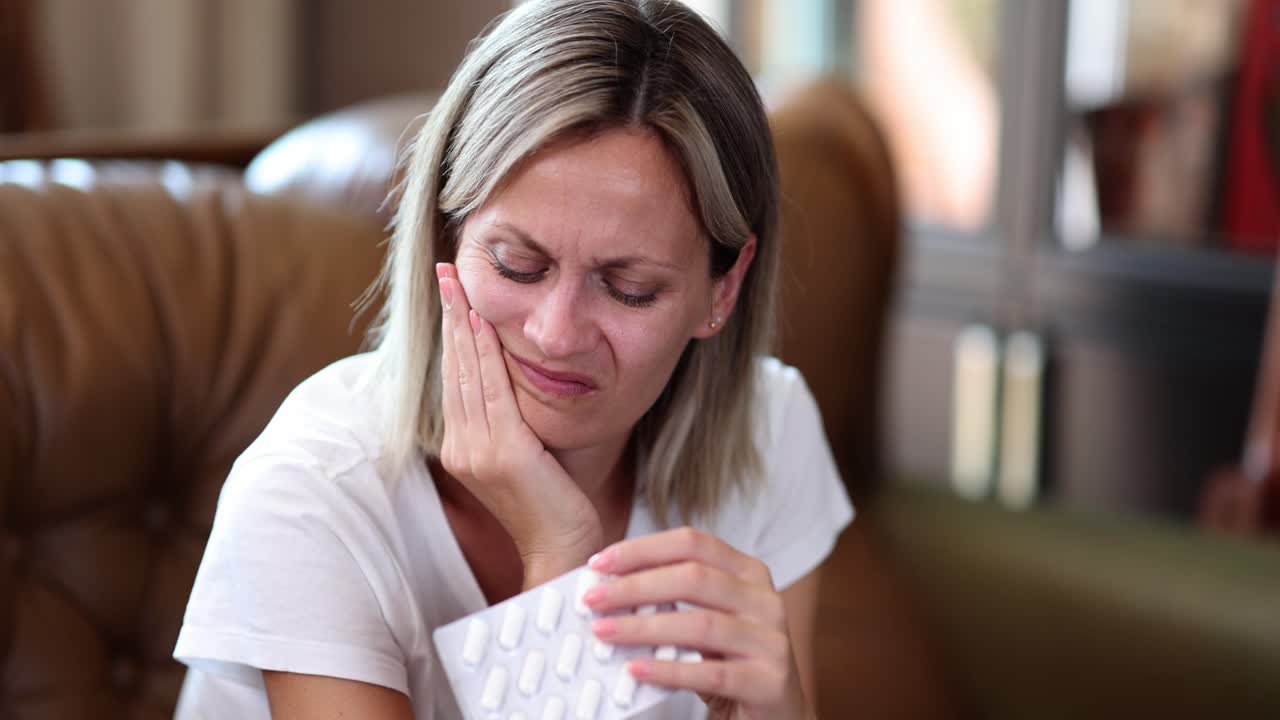 Woman suffering from toothache holding medication