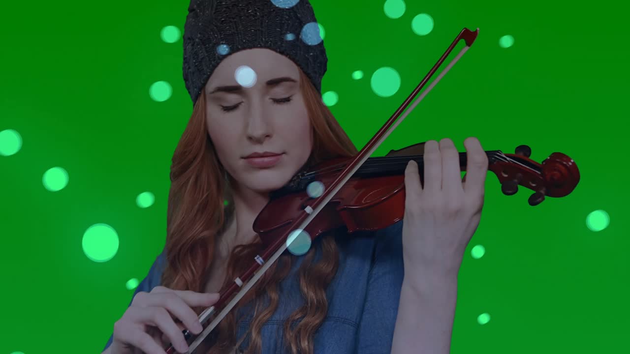Violinista che alza l'archetto tenendo il violino ed esegue musica con cerchi di luce fluttuanti su greenscreen