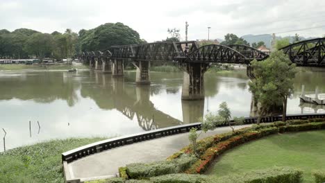 Una-Inclinación-Que-Establece-La-Toma-Del-Icónico-Puente-De-La-Segunda-Guerra-Mundial-Sobre-El-Río-Kwai,-Kanchanaburi,-Tailandia