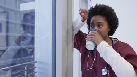 Tired-african-american-female-doctor-drinking-coffee-in-hospital,-slow-motion