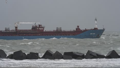 cargo ship in rough seas with breakwater