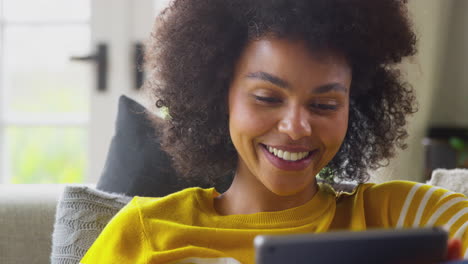 Close-Up-Of-Woman-Relaxing-On-Sofa-At-Home-Using-Digital-Tablet-To-Stream-Movie