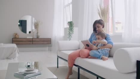 familia feliz madre y niño hijo usando tableta digital sentado en el sofá sonriente padre madre con hijo sosteniendo computadora mirando la pantalla hacer compras en línea hacer video llamadas ver dibujos animados