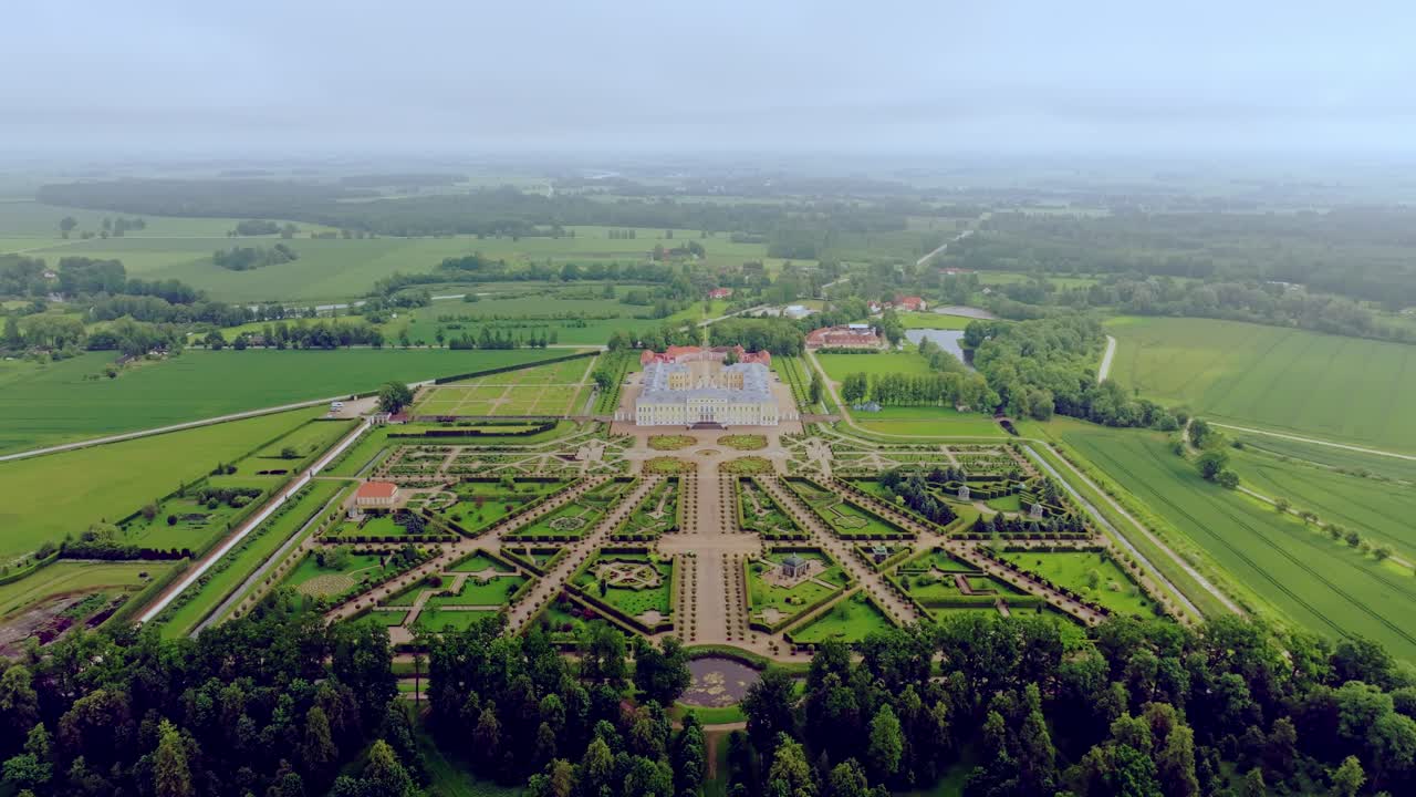 Majestic aerial journey retreats from Baroque palace across gardens into clouds