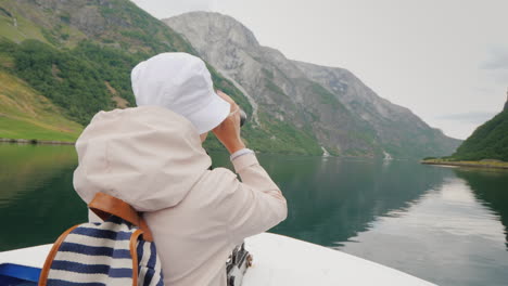 a woman is standing on the bow of the ship looking through binoculars cruise on the fjords of norway