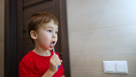 adorable caucasian baby boy stands cleaning his teeth. happy toddler kid smiles as he brushes teeth.