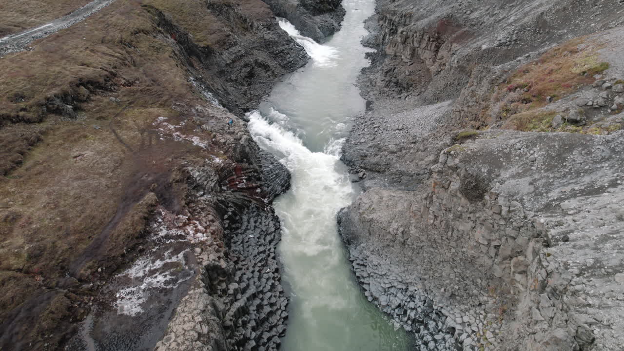 una lenta panorámica aérea que revela el cañón de studlagil, islandia, tallado por un río glacial