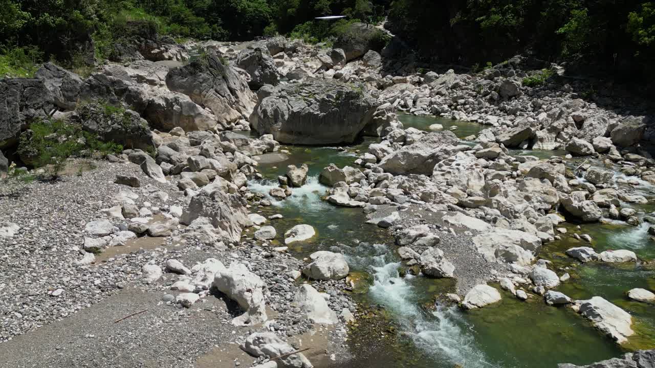 The shot pulls away revealing the river, land, surrounding rocks, and lush trees around Tinipak River, Philippines